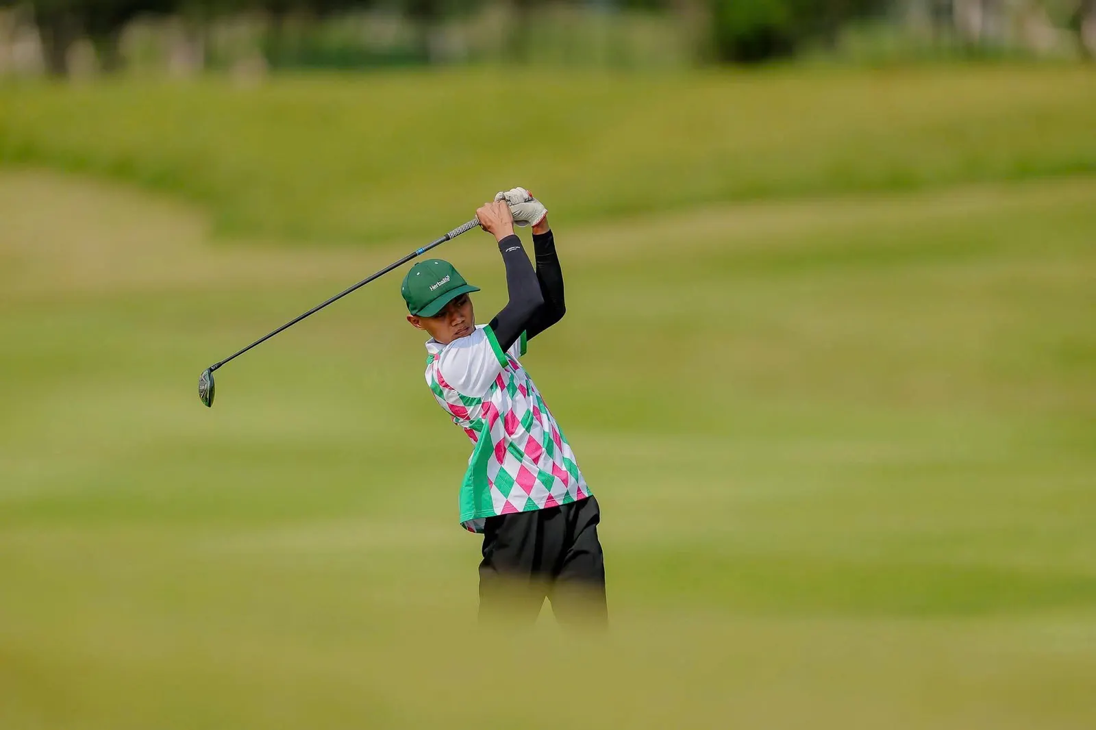 A young player swinging on the fairway