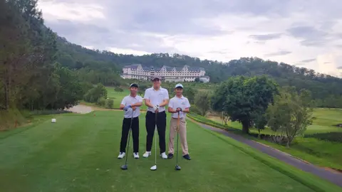 Nhóm trên sân golf đồi, có nhà câu lạc bộ phía sau
