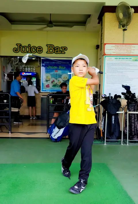Bé trai áo vàng vung gậy